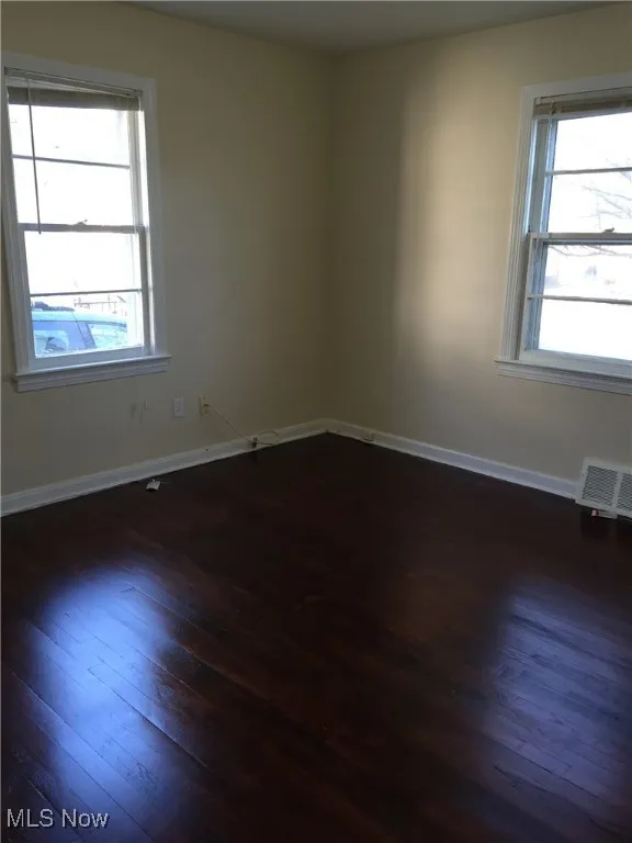 Empty room featuring dark wood finished floors and baseboards