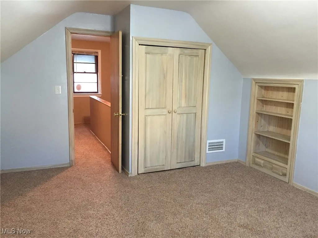 Additional living space featuring lofted ceiling, carpet flooring, and built in features