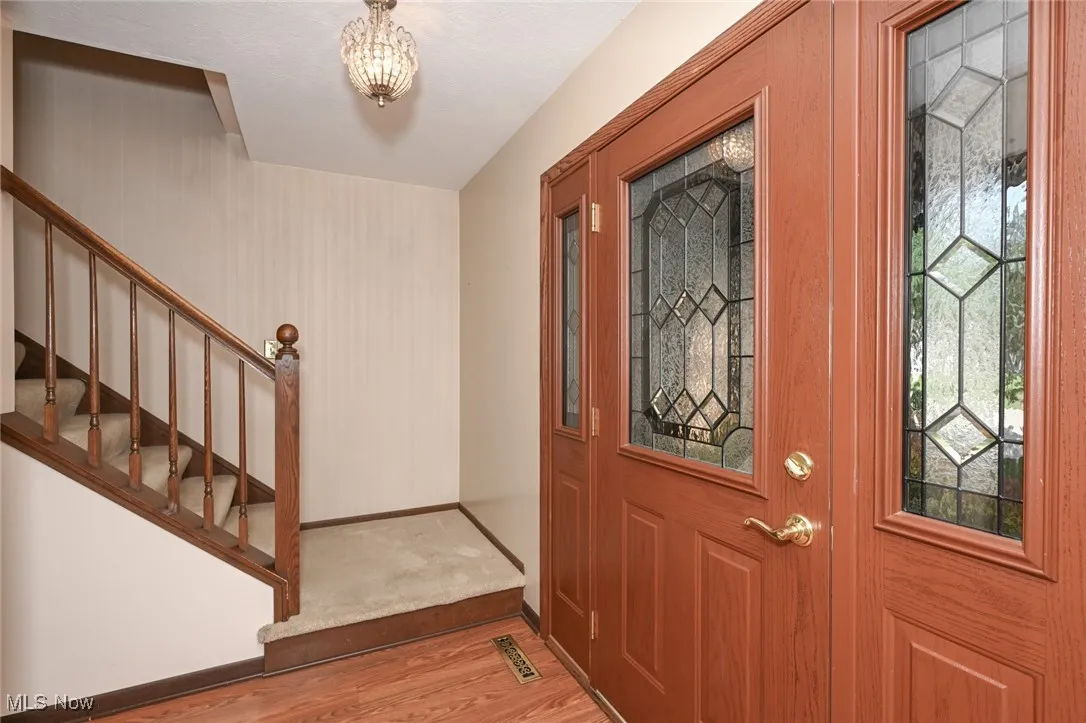 Foyer featuring stairway, wood finished floors, and a chandelier