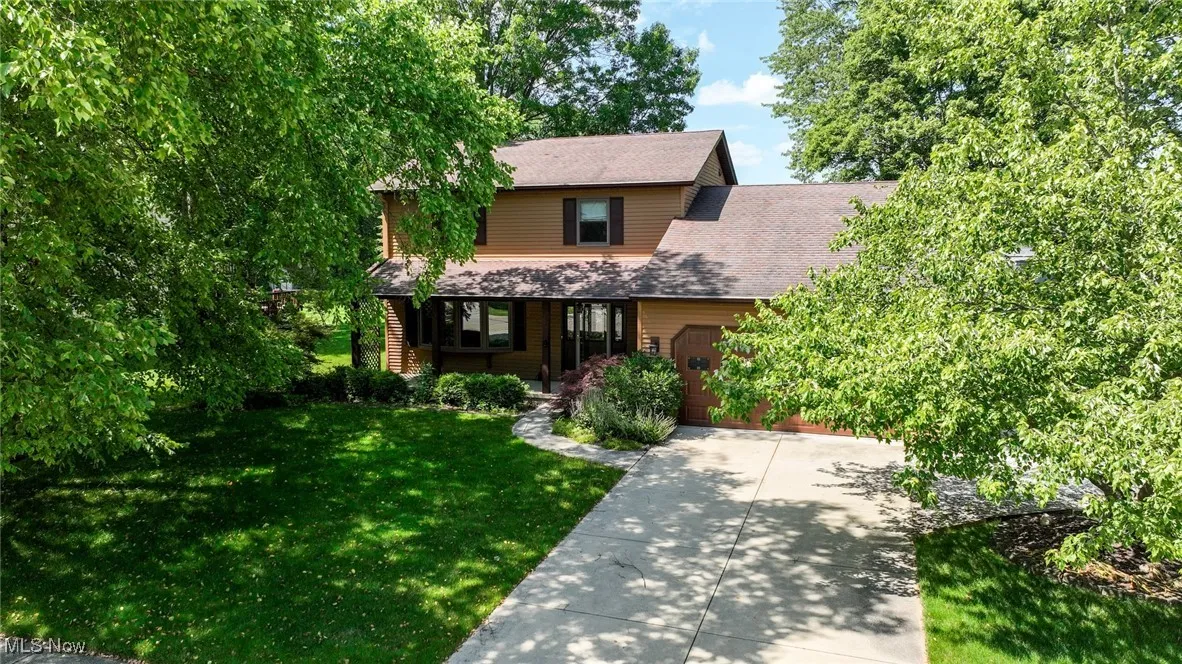 View of front of home featuring an attached garage, a front lawn, concrete driveway, and covered porch