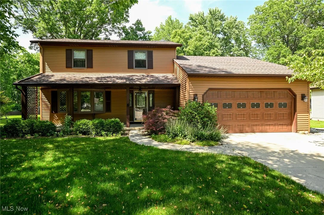 View of front with driveway, a garage, a front yard, and a porch