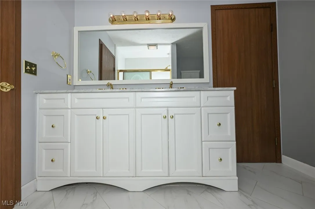 Full bathroom with marble look tile flooring and double vanity