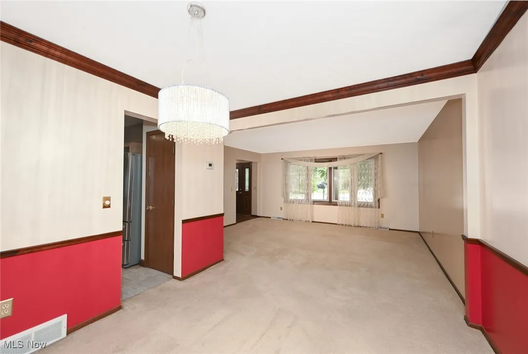Dining room with light carpet, a chandelier, and crown molding