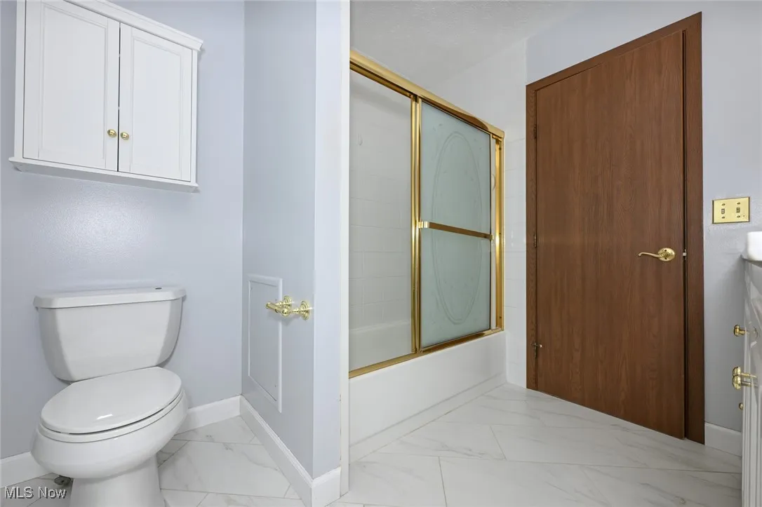 Bathroom with marble look tile flooring, combined bath / shower with glass door, and vanity