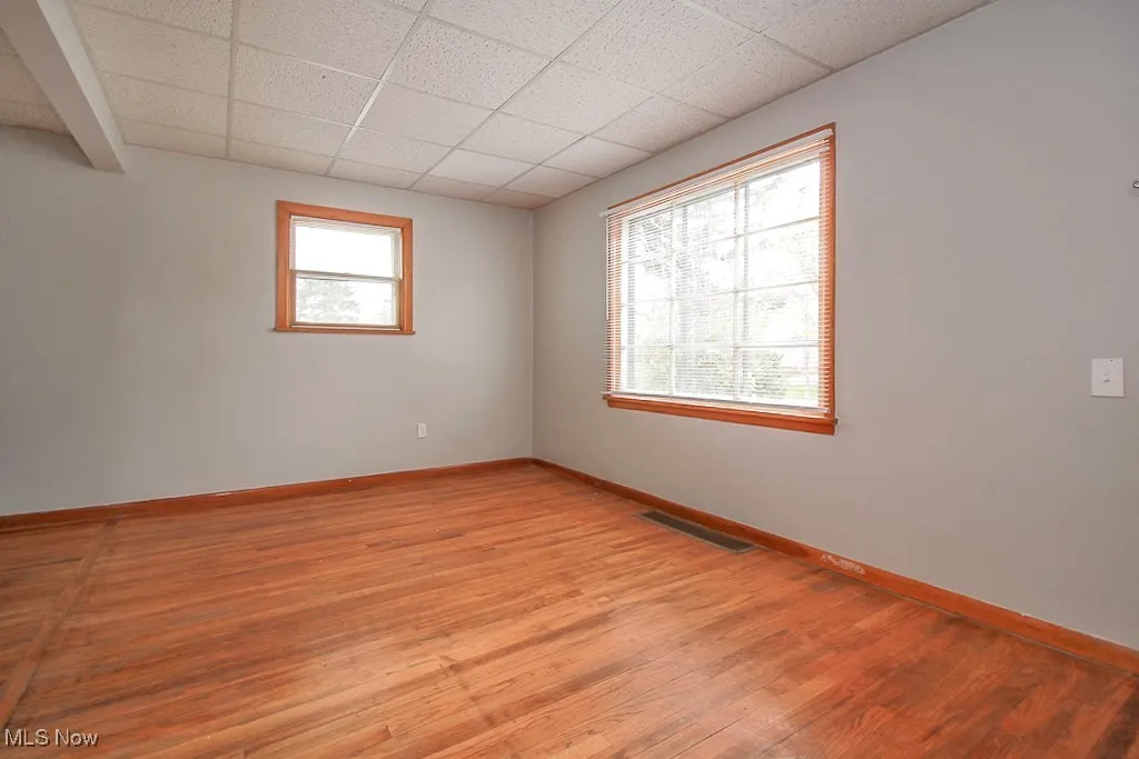 Unfurnished room with light wood finished floors and a paneled ceiling