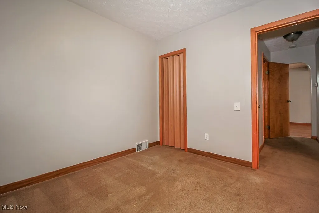 Empty room with light carpet and a textured ceiling