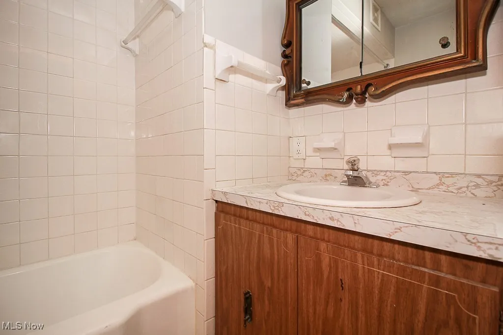 Bathroom featuring vanity, backsplash, and  shower combination