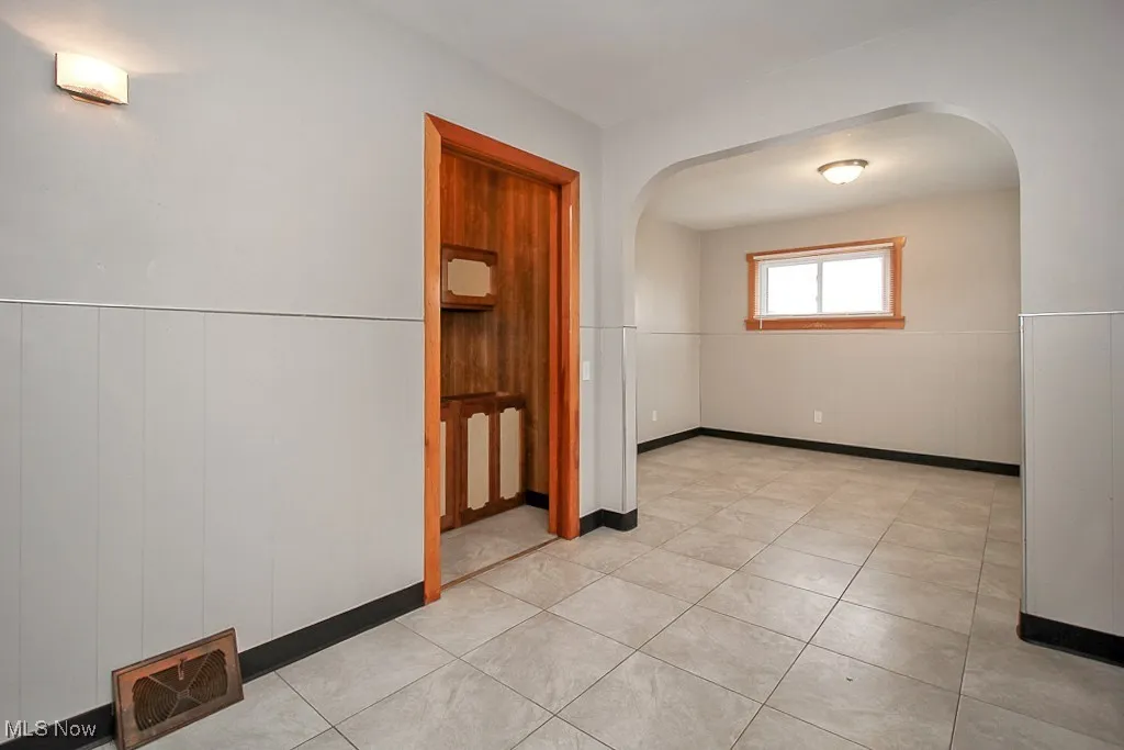 Empty room with arched walkways and light tile patterned floors