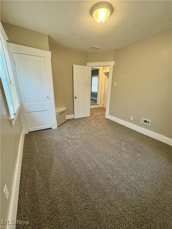 Unfurnished bedroom with a textured ceiling and carpet flooring