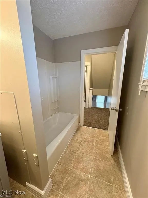 Bathroom with a textured ceiling and baseboards
