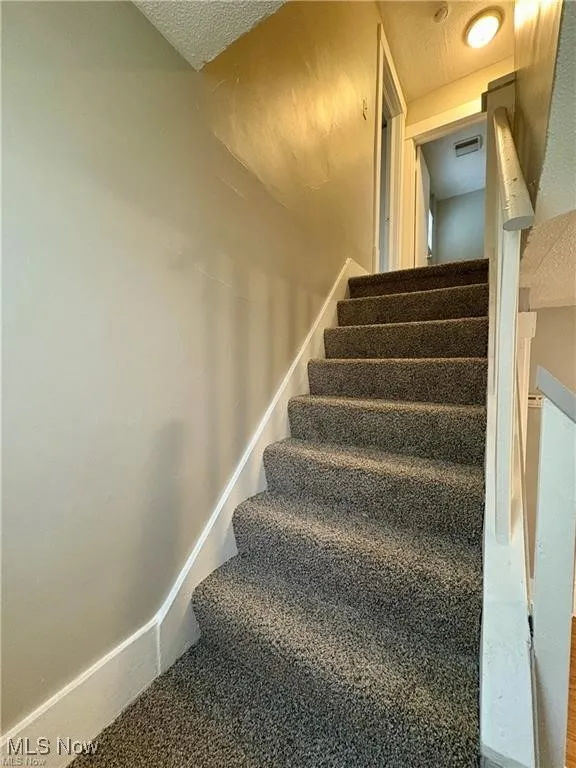 Staircase featuring a textured ceiling