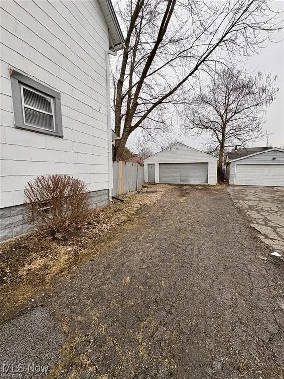 View of side of property featuring a detached garage and an outbuilding
