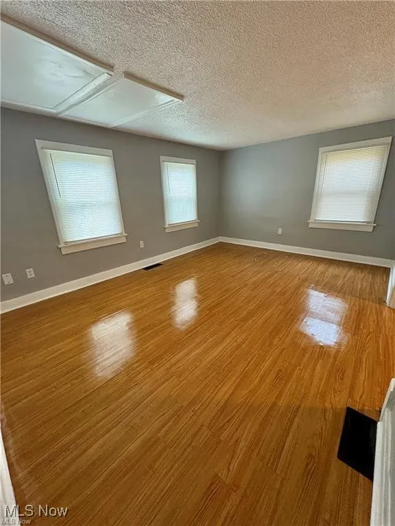 Empty room featuring wood finished floors and a textured ceiling