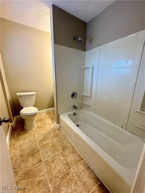 Bathroom featuring a textured ceiling and  shower combination