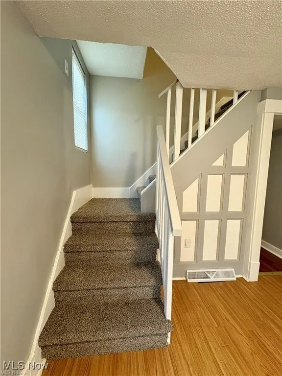 Stairs featuring a textured ceiling and wood finished floors