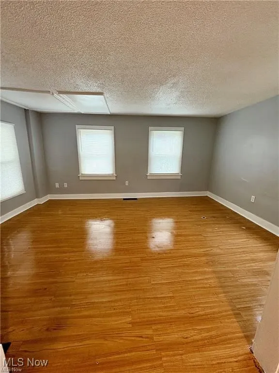 Unfurnished room featuring a textured ceiling, healthy amount of natural light, and light wood-style flooring