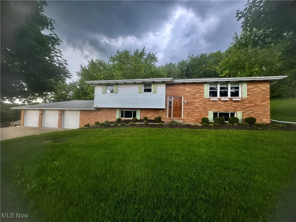 Bi-level home with brick siding, a front lawn, and concrete driveway