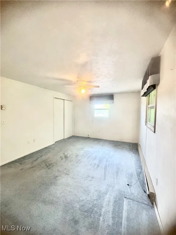 Carpeted empty room featuring a textured ceiling and ceiling fan