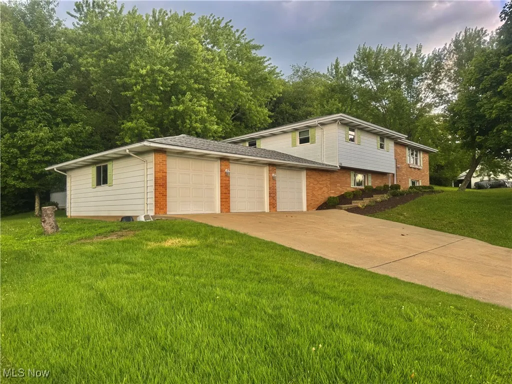 View of front facade with an attached garage, brick siding, a front lawn, and concrete driveway
