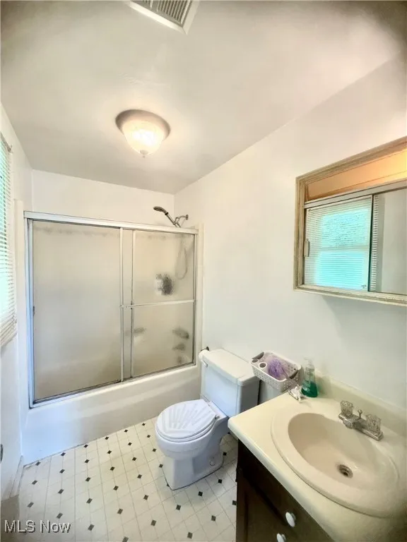 Bathroom featuring vanity, enclosed tub / shower combo, and tile patterned floors