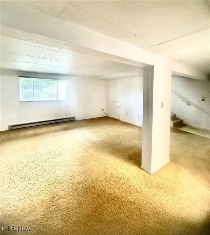 Basement featuring a baseboard radiator, stairway, and carpet floors
