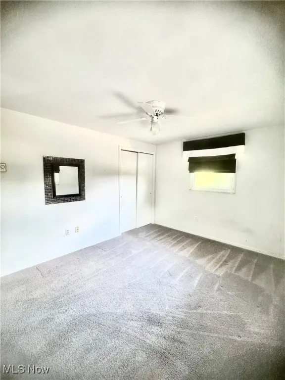 Carpeted spare room featuring ceiling fan