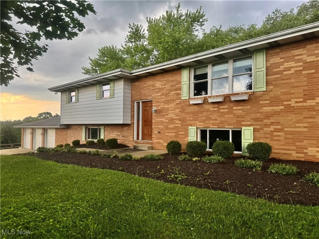 Bi-level home featuring brick siding, a front yard, and driveway