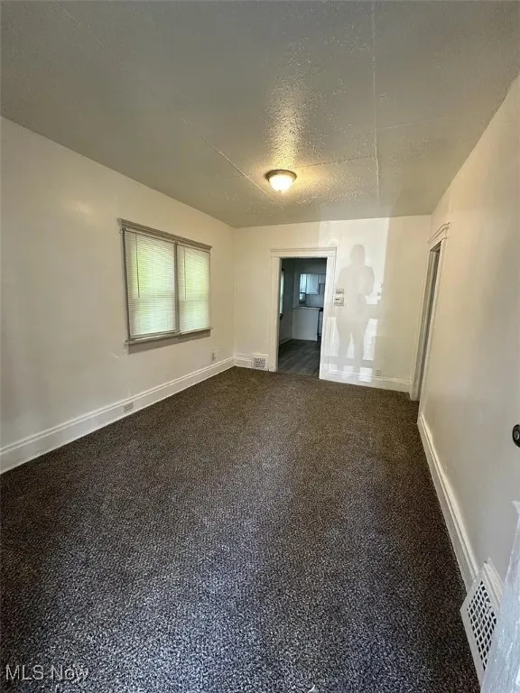 Spare room featuring a textured ceiling and baseboards