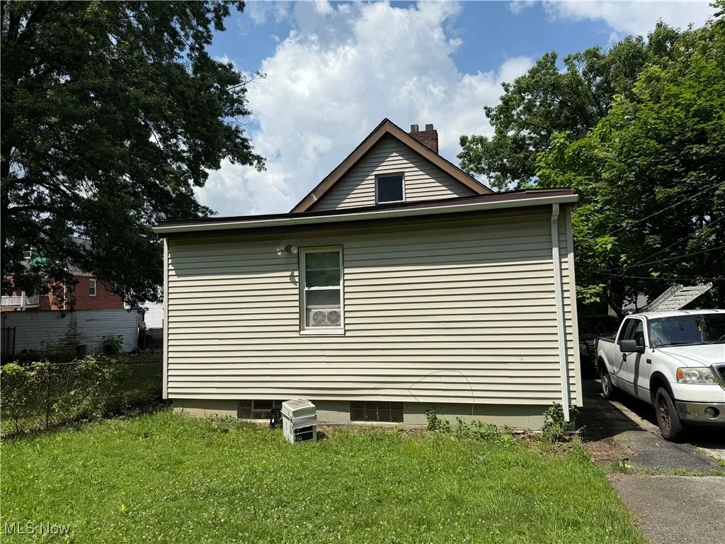 View of property exterior with a chimney and a lawn