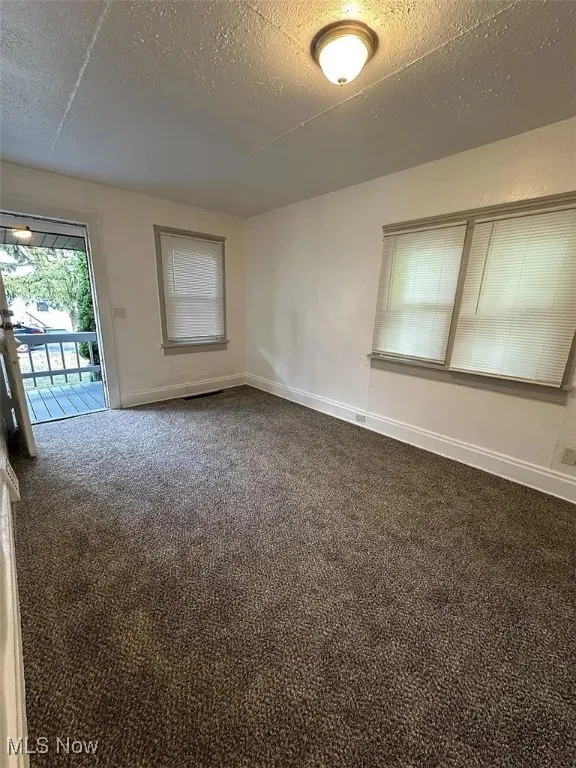 Carpeted spare room with baseboards and a textured ceiling