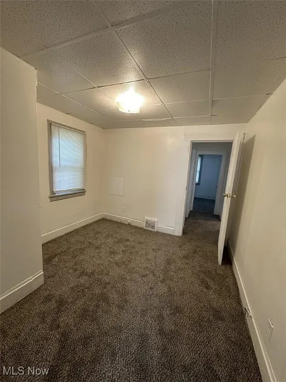 Spare room featuring a paneled ceiling and dark carpet