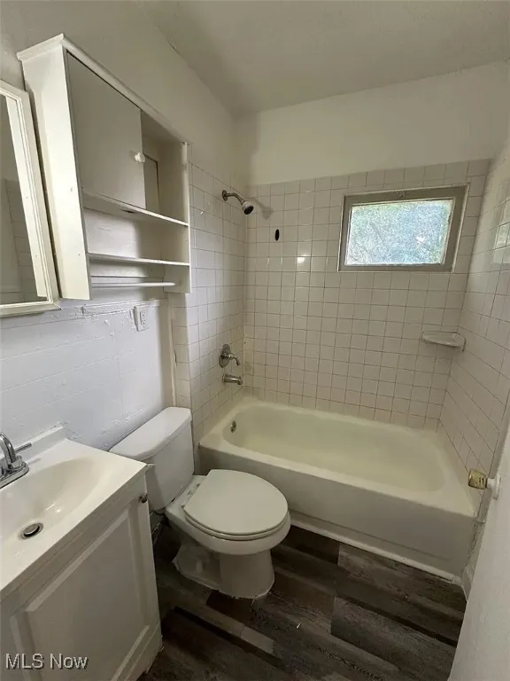 Full bath featuring wood finished floors, vanity, and washtub / shower combination