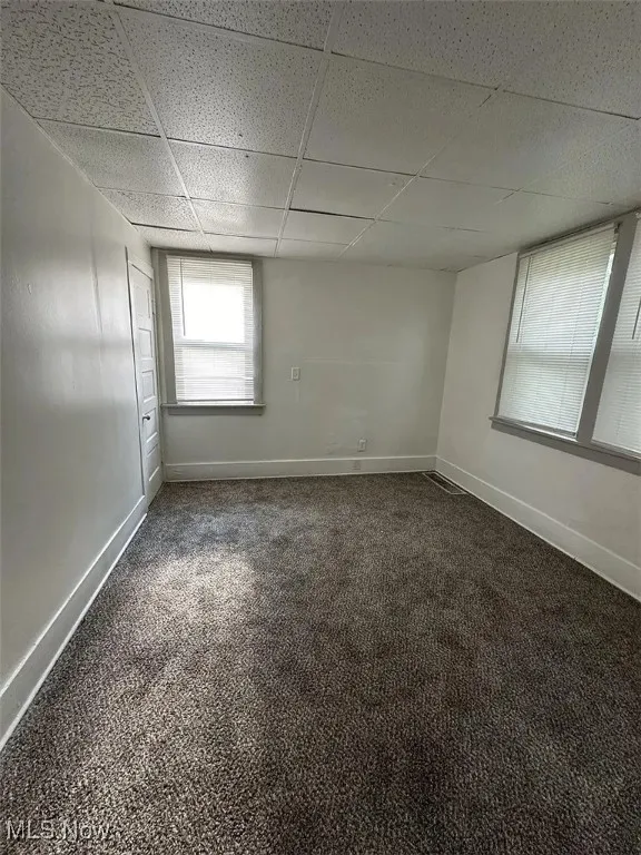 Spare room featuring a paneled ceiling and dark carpet
