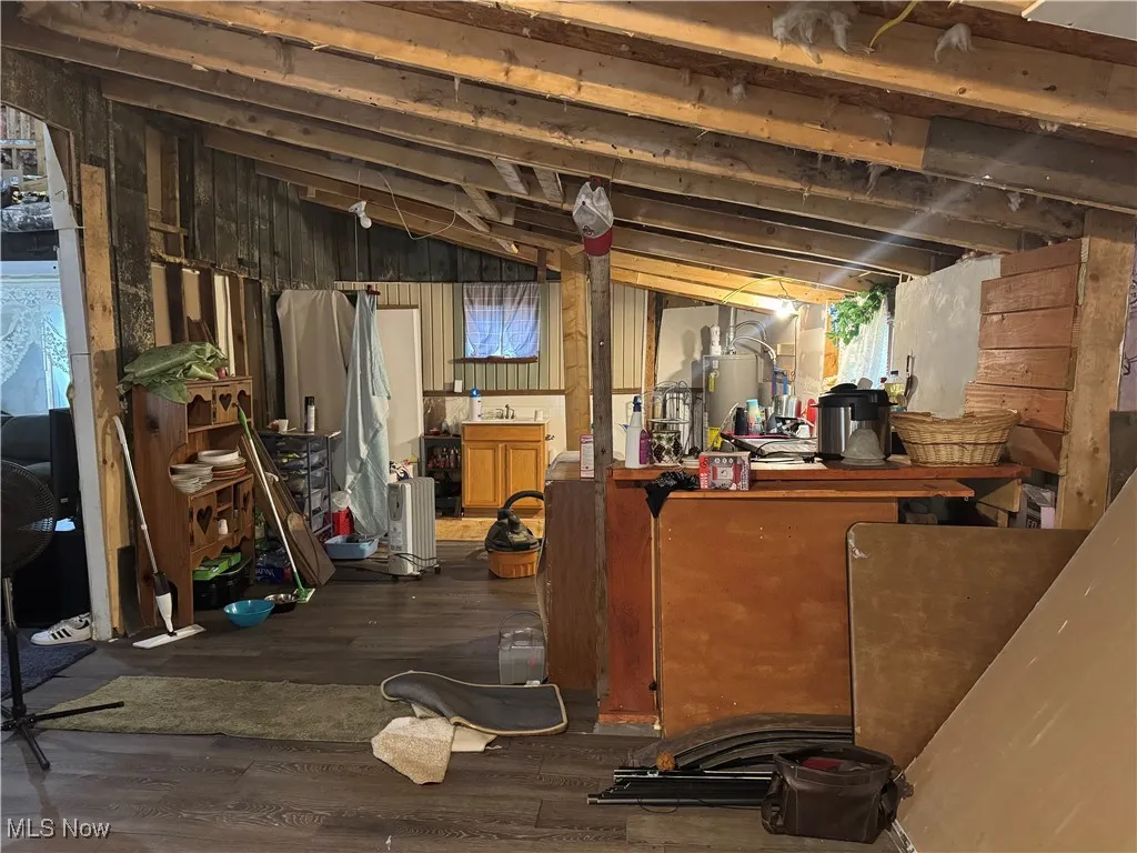 Unfinished below grade area featuring water heater and wood finished floors
