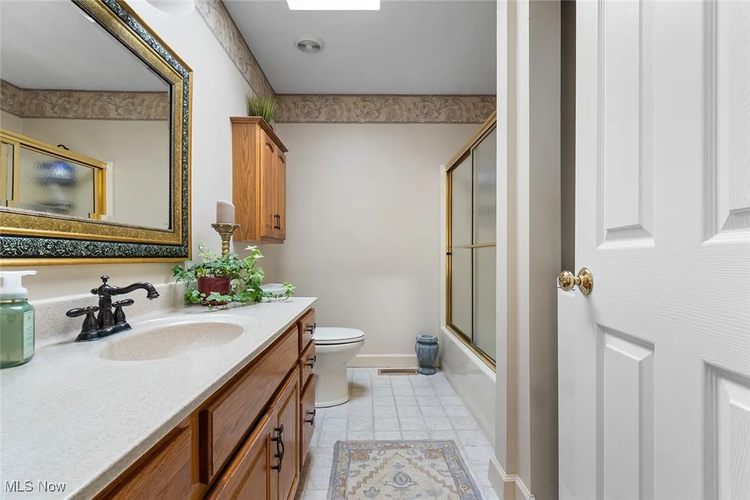 Bathroom with vanity and enclosed tub / shower combo
