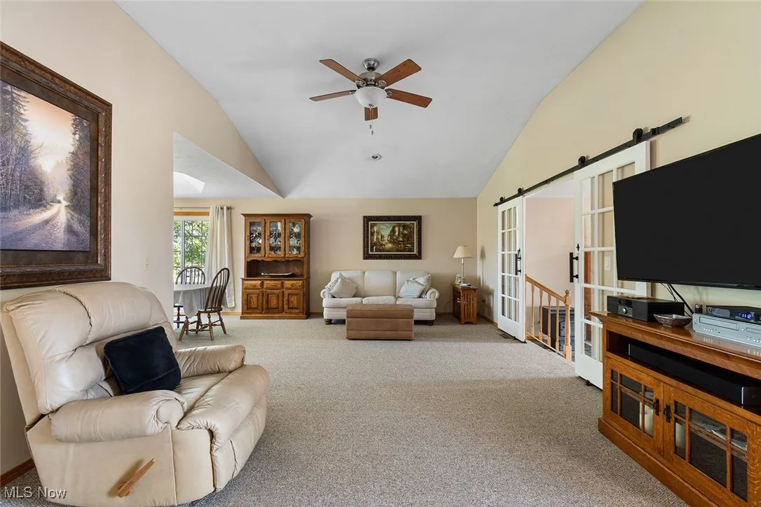 Carpeted living room featuring vaulted ceiling and ceiling fan