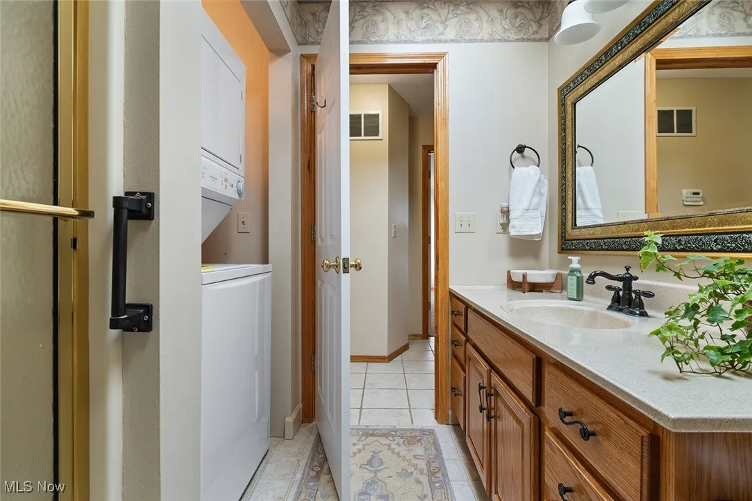 Bathroom with estacked washer and dryer, vanity, and tile patterned flooring