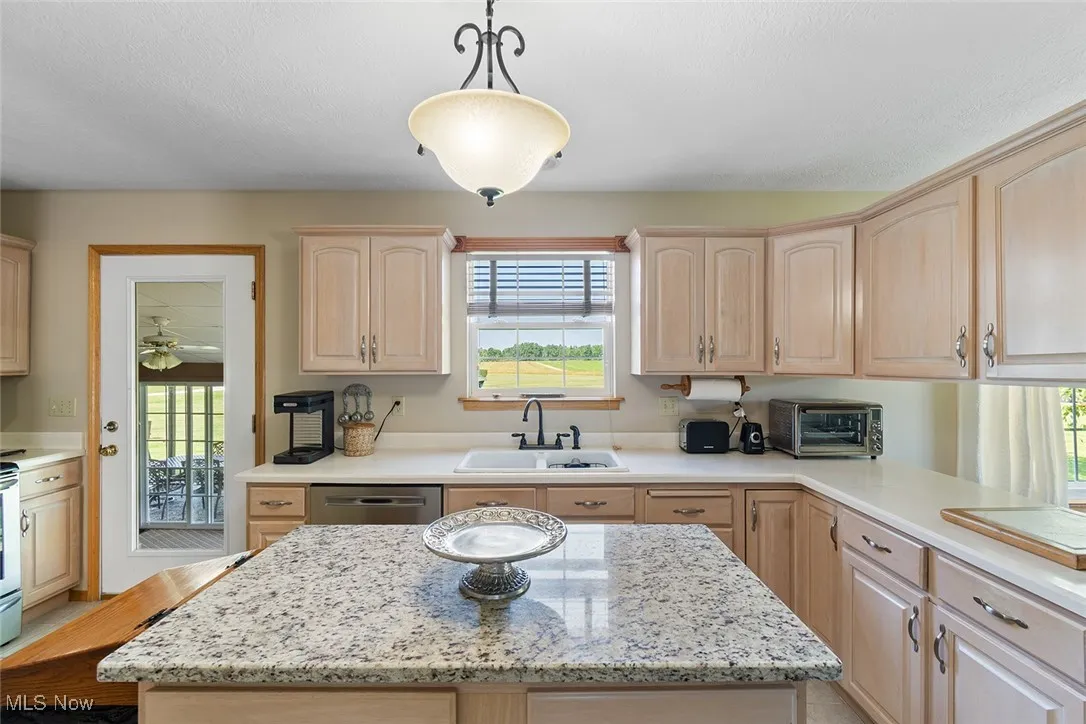 Kitchen with light brown cabinets, stainless steel dishwasher, plenty of natural light, and a center island
