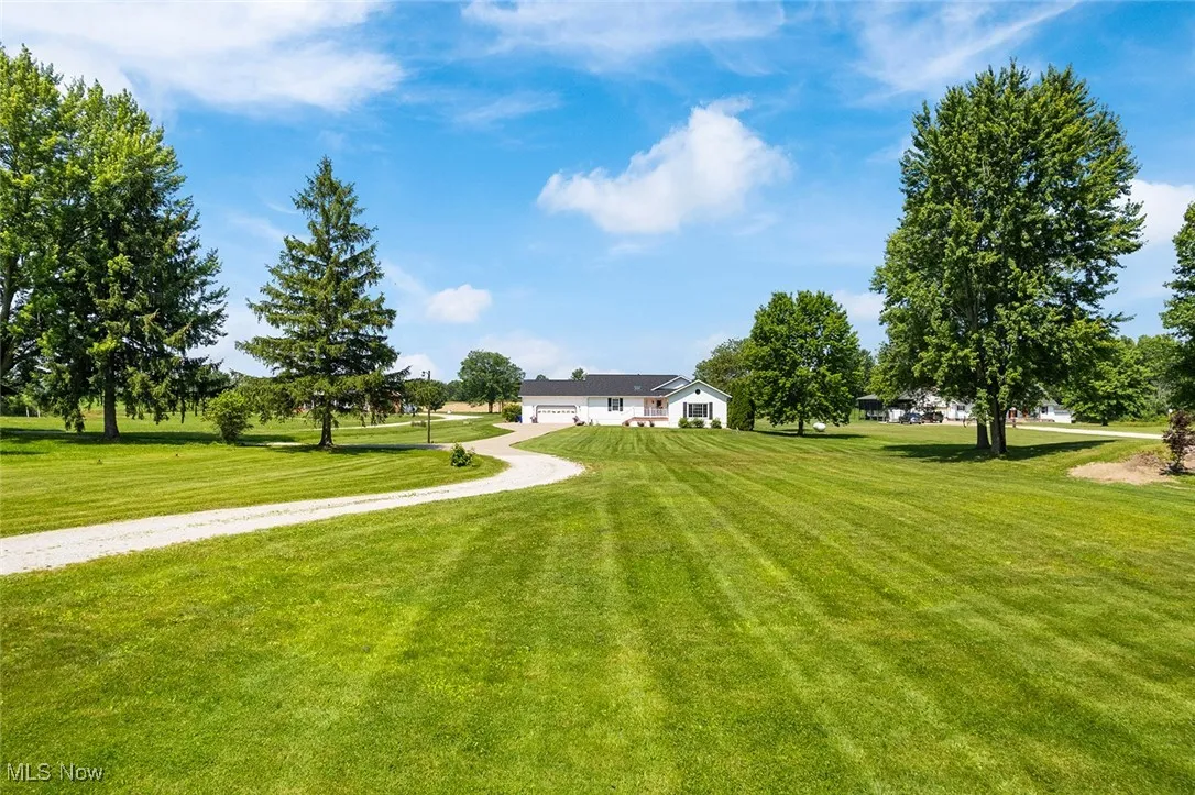 View front of structure with grassy yard, driveway and an attached garage