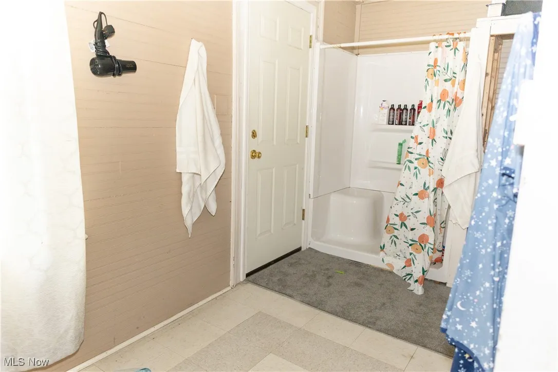 Full bath with a shower with shower curtain and tile patterned floors