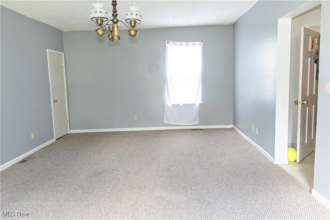 Spare room with a chandelier and carpet floors