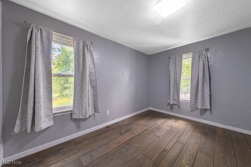 Empty room featuring hardwood / wood-style flooring and a textured wall