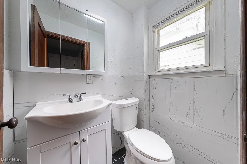 Half bath featuring vanity, tile walls, and wainscoting