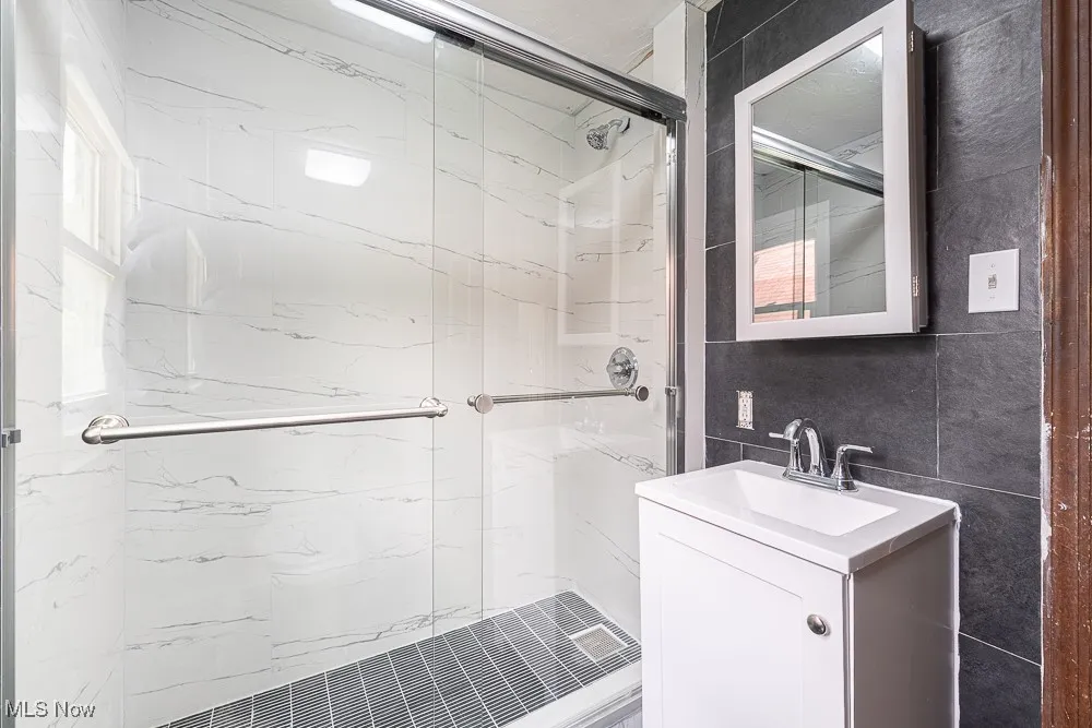 Bathroom featuring a marble finish shower and vanity