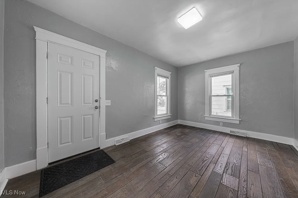 Foyer entrance with dark wood finished floors and a textured wall