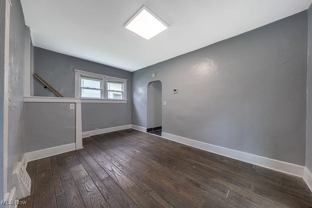 Spare room with hardwood / wood-style flooring, arched walkways, and a textured wall