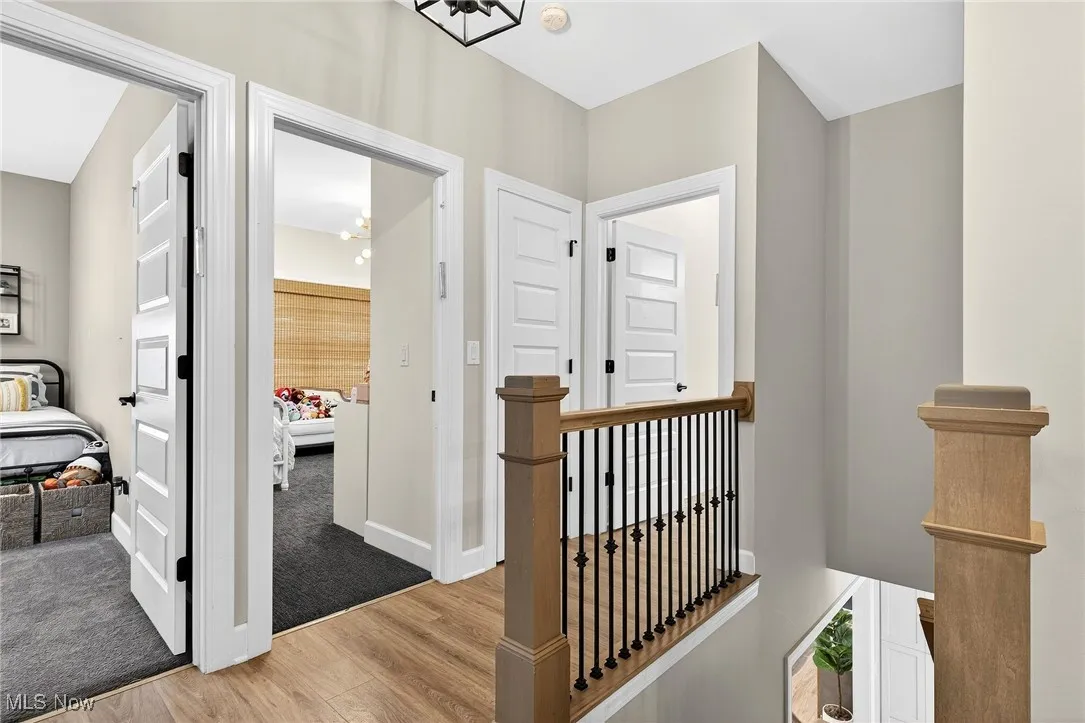 Hallway featuring an upstairs landing, light wood-style flooring, and a chandelier