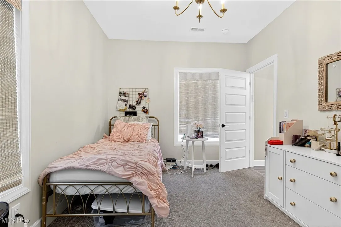 Carpeted bedroom with a chandelier and baseboards