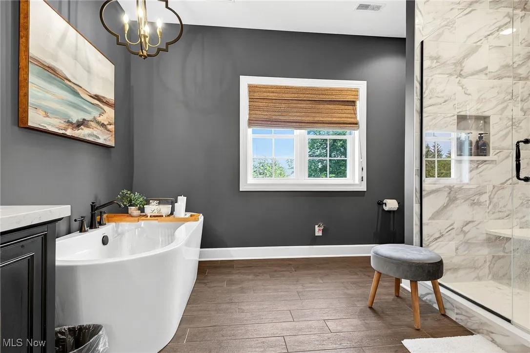 Full bathroom with a freestanding bath, a marble finish shower, hardwood / wood-style floors, vanity, and a chandelier