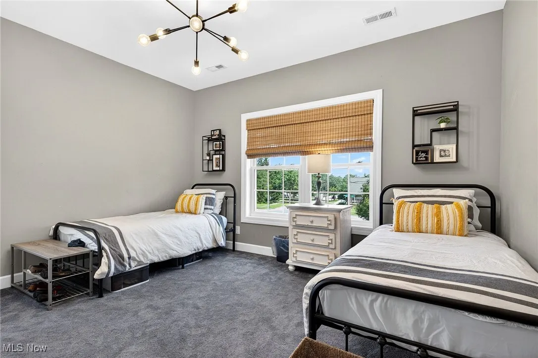 Bedroom featuring a chandelier and dark carpet